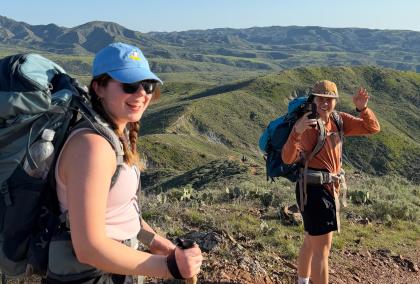 Two Hex team members with backpacks hiking through arid mountain terrain