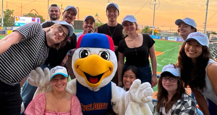 Hex team members posing with the Brooklyn Cyclones mascot at a baseball game at sunset