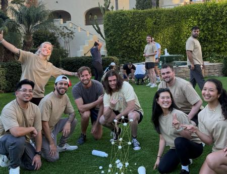 Hex team members playing a tower-building challenge on a lawn during a company offsite